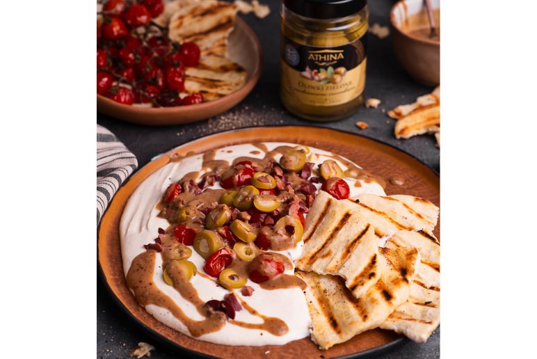 Pasta z sera feta posypana oliwkami z domowymi chlebkami, w tle oliwki od Athina