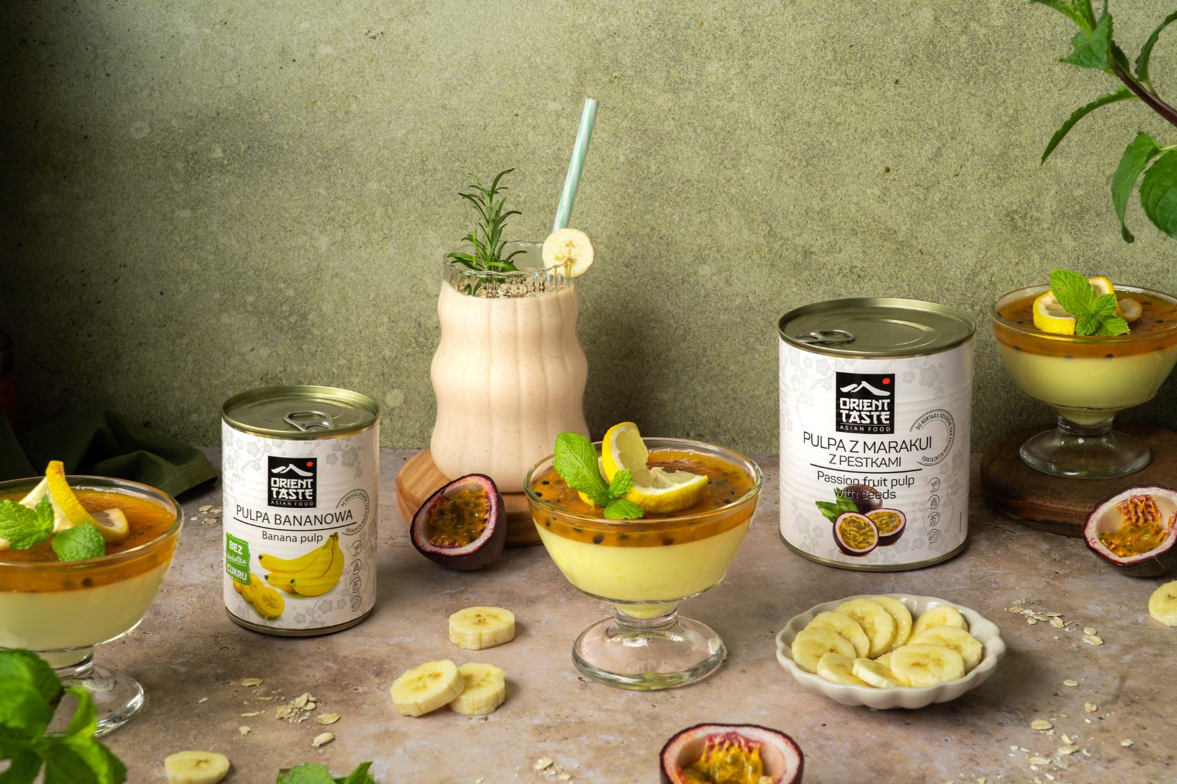 Jogurtowa pianka cytrynowa z marakują w pucharku, obok puszki z pulpami od orient taste, świeża marakuja, banan