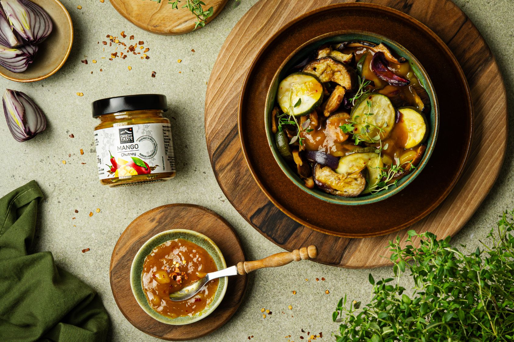 Warzywa pieczone, cukinia bakłażan na talerzu zapiekane w sosie mango chutney. Obok miseczka wypełniona sosem.