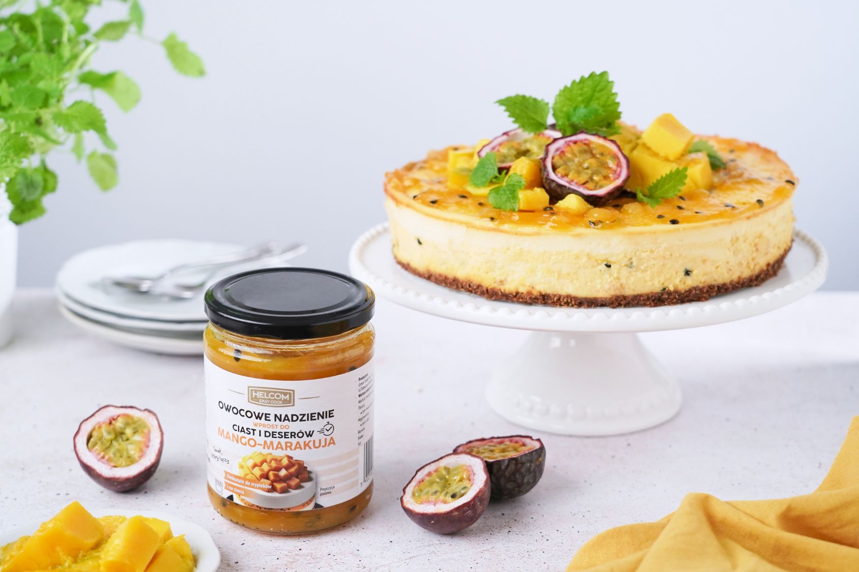 SERNIK MANGO – MARAKUJA na paterze, obok niej stoi nadzienie z marakuja i mango od Helcom Easy Cook i pokrojona marakuja na pół
